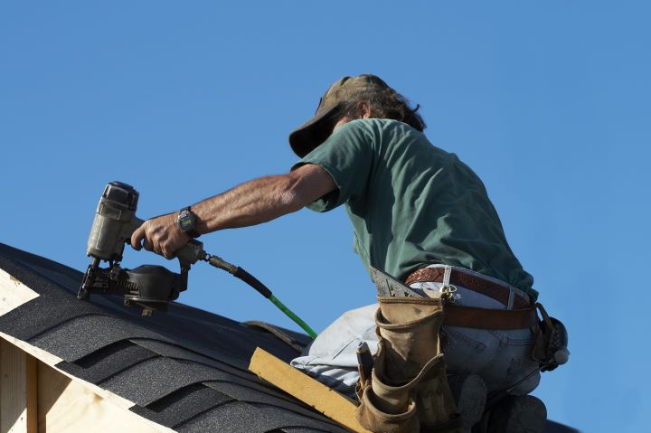 roofer repairing shingles on home